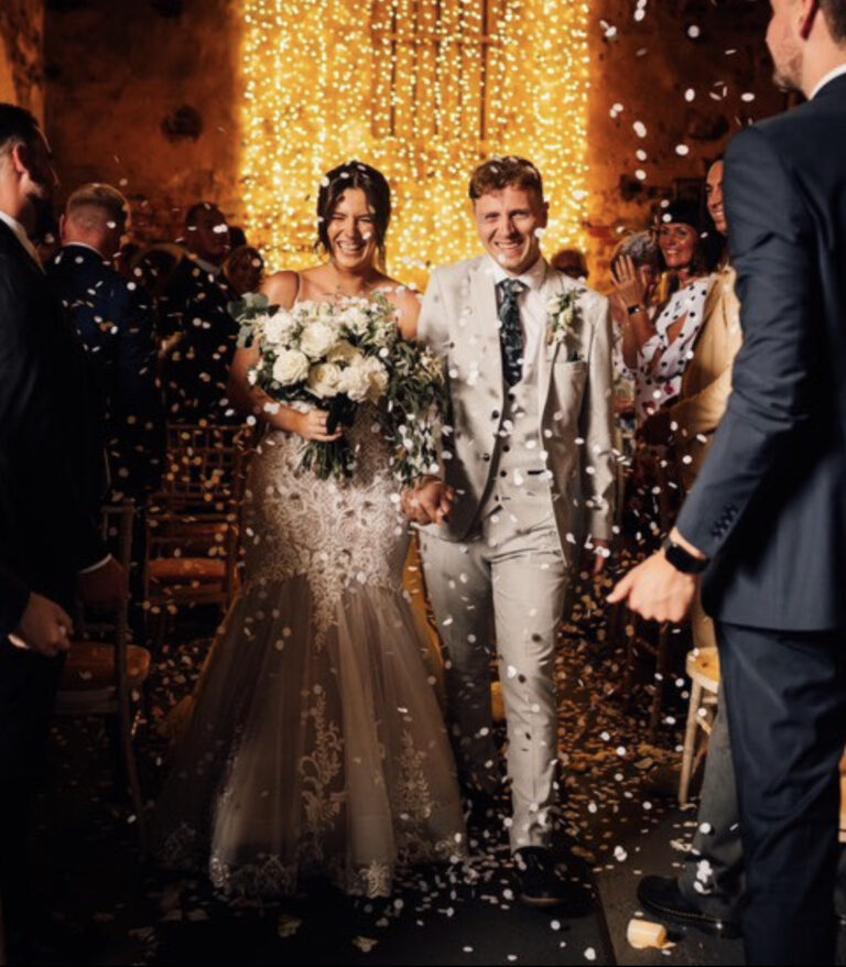 Wedding Flowers. Bride and groom walking through confetti shot with flowers in hand.