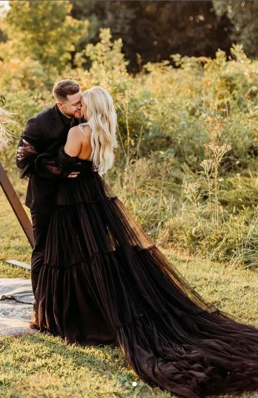 Just married. Bride and groom kiss while smiling. Wearing black wedding dress