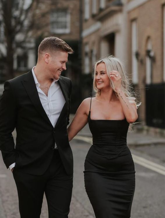 Bride and groom walking whilst laughing at eachother. Bride wears black wedding dress