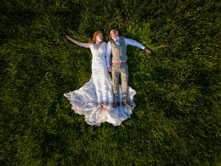 Bride and Groom laying in field by Jane Ball Photography
