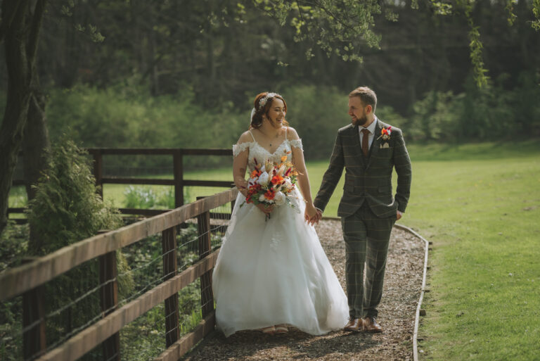 Bride and Groom walking through fields by Furness Digital Photography